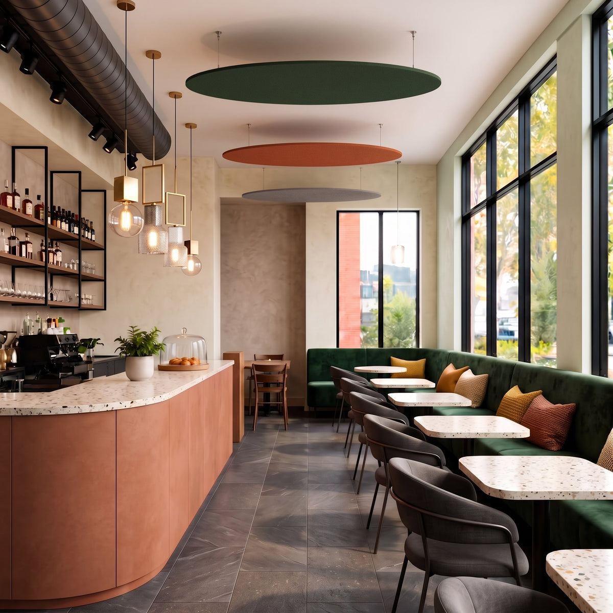 Round felt ceiling rafts in green, rust and cream hanging above the counter and seating of a café