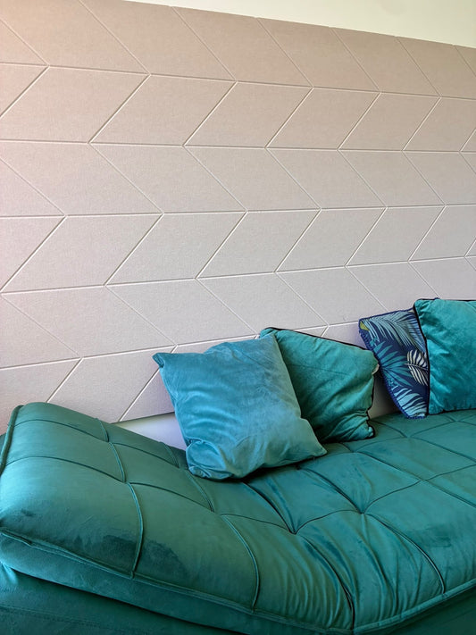 A feather-engraved 12mm PET felt wall panel in Wheat on the wall of a therapist's room, behind a teal velvet sofa.