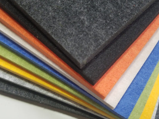 A stack of PET felt sheets in black, grey, orange, white, blue, green and yellow, showing the colour range and the thickness of the board