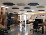 Hexagon felt ceiling rafts in blue, black and natural hanging above desks in an open-plan office