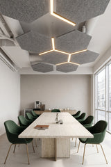 Grey hexagon felt ceiling rafts with light lines between them, above a stone meeting table