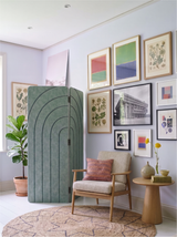 Sage green arches engraved folding room divider screening a corner in a domestic interior