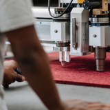 Person operating a CNC machine on a red material