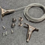 Metal fishing reel components including a handle, cable, and various parts on a gray surface.