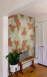 A hallway feature wall of Einstein hat PET felt tiles in green, tan and cream, beside a wooden bench
