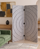 A three-panel folding room divider made of textured gray felt with a black concentric circle pattern, standing in a modern living room next to a green sofa.