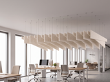 A run of natural cotton Felted trapezoid acoustic baffles hung on edge on wires above an open plan office, with desks and task chairs below full height windows onto a bright cityscape.