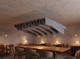 A run of grey Felted trapezoid acoustic baffles with raked staggered blades hung below an exposed concrete ceiling in a restaurant dining room, above timber tables lit by copper pendants and table lamps.