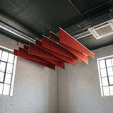 Twill felt ceiling baffles in Dark Rouge in a brick-walled room with exposed services